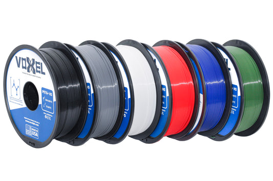 Voxel 3D printing PETG filament spools in black, white, red, blue, green, and grey colors on a white background. All filaments are made in the USA. It is a bulk bundle for PETG.